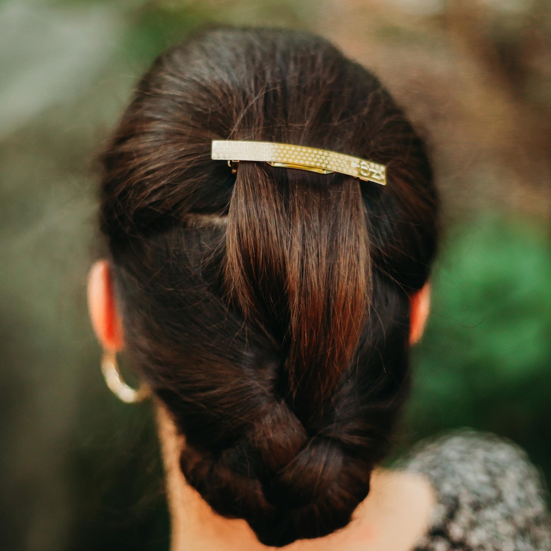 FEMME BRUNE VUE DE DOS LES CHEVEUX RELEVES ET PORTANT UNE BARRETTE DOREE DECOREE AVEC MOTIF PETITES FLEURS