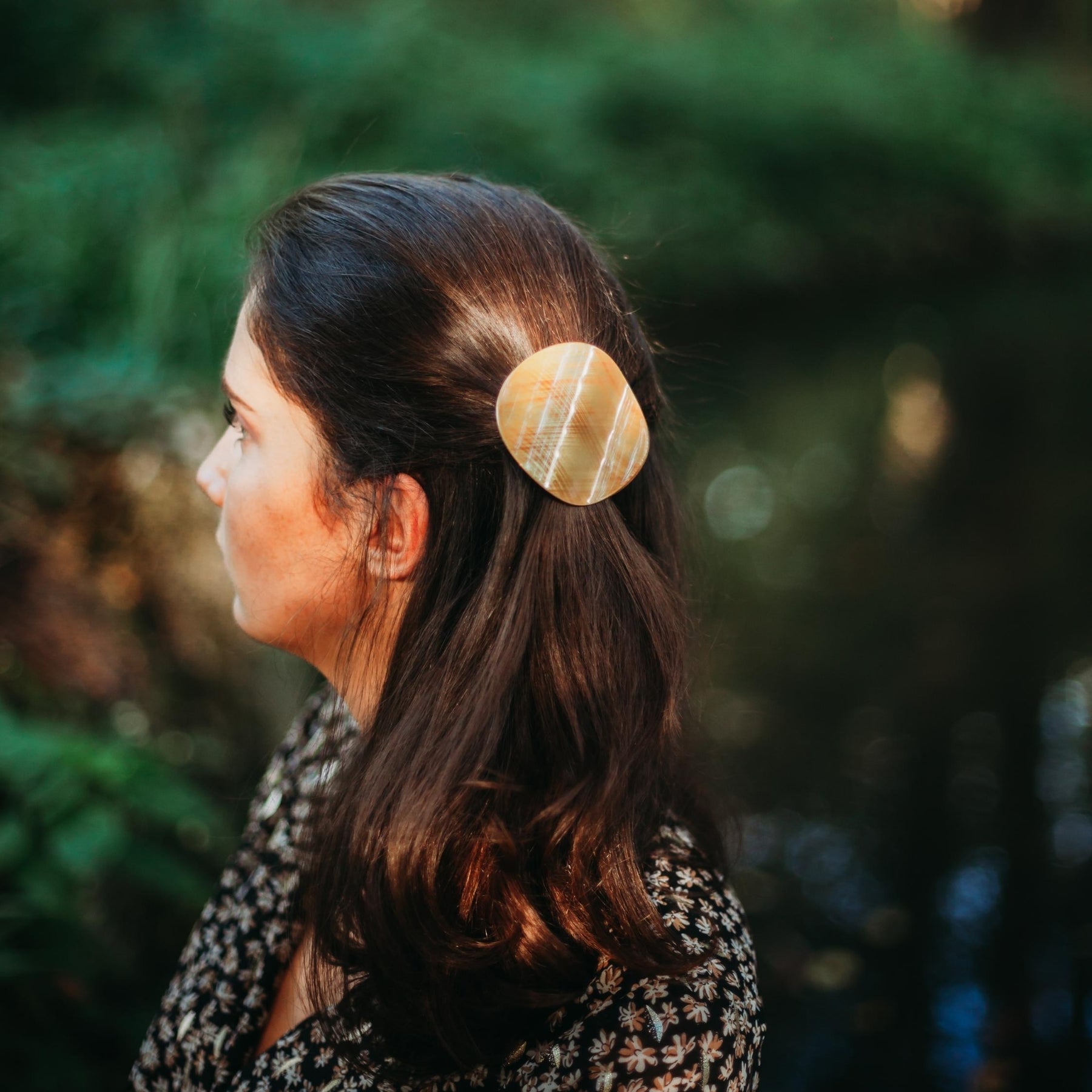 FEMME BRUNE VUE DE PROFIL PORTANT UNE PINCE RONDE DANS LES CHEVEUX