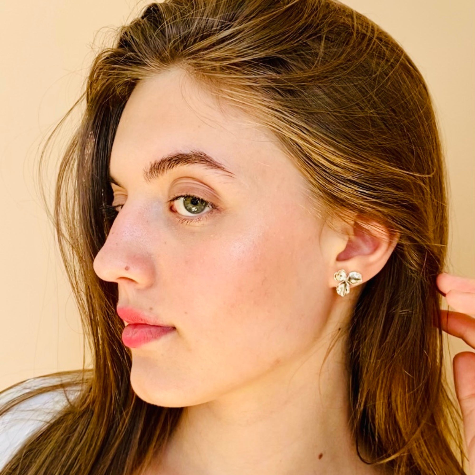 Femme avec boucles d'oreilles tendances argentées puces fleur