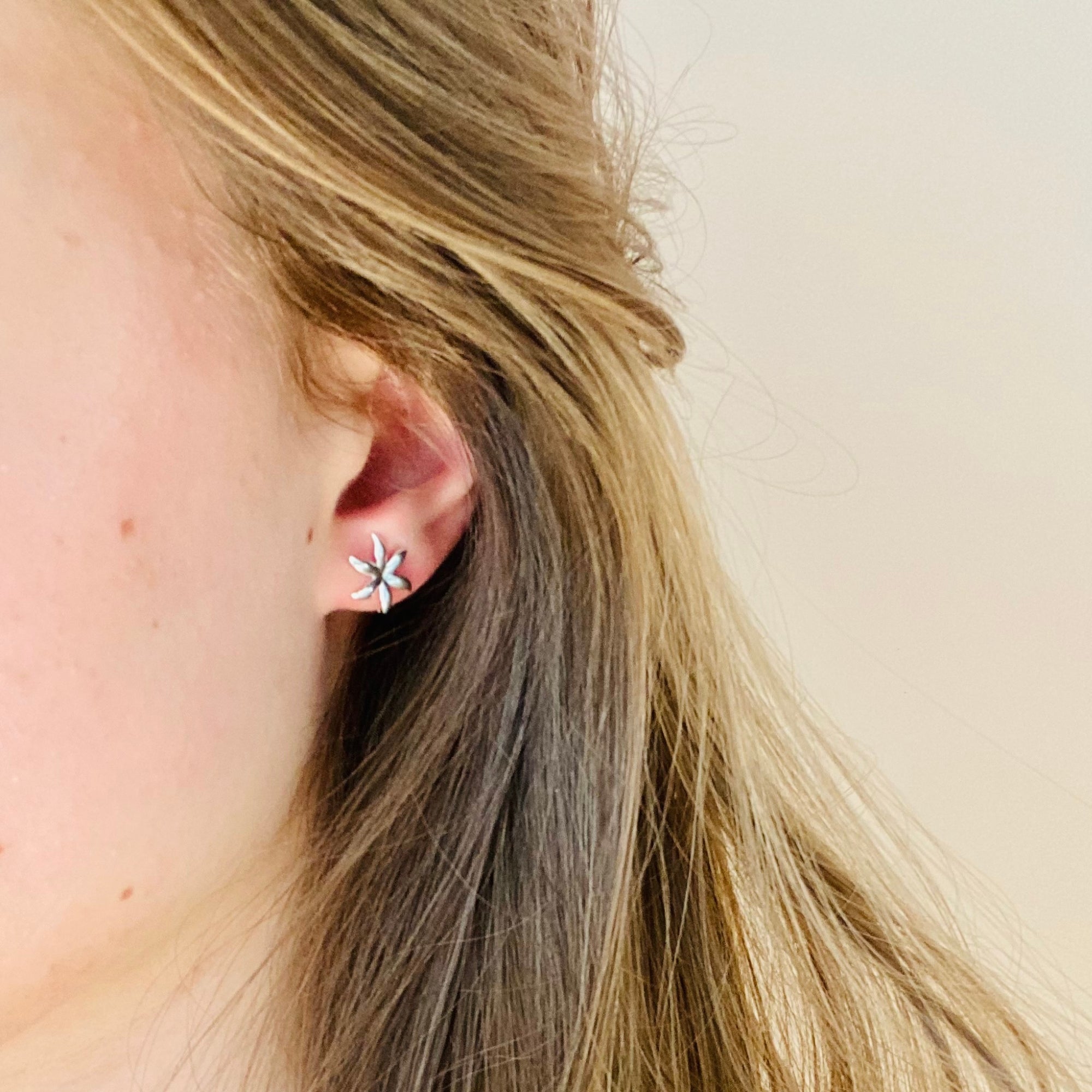 Femme avec boucles d'oreilles argentées puces étoiles 