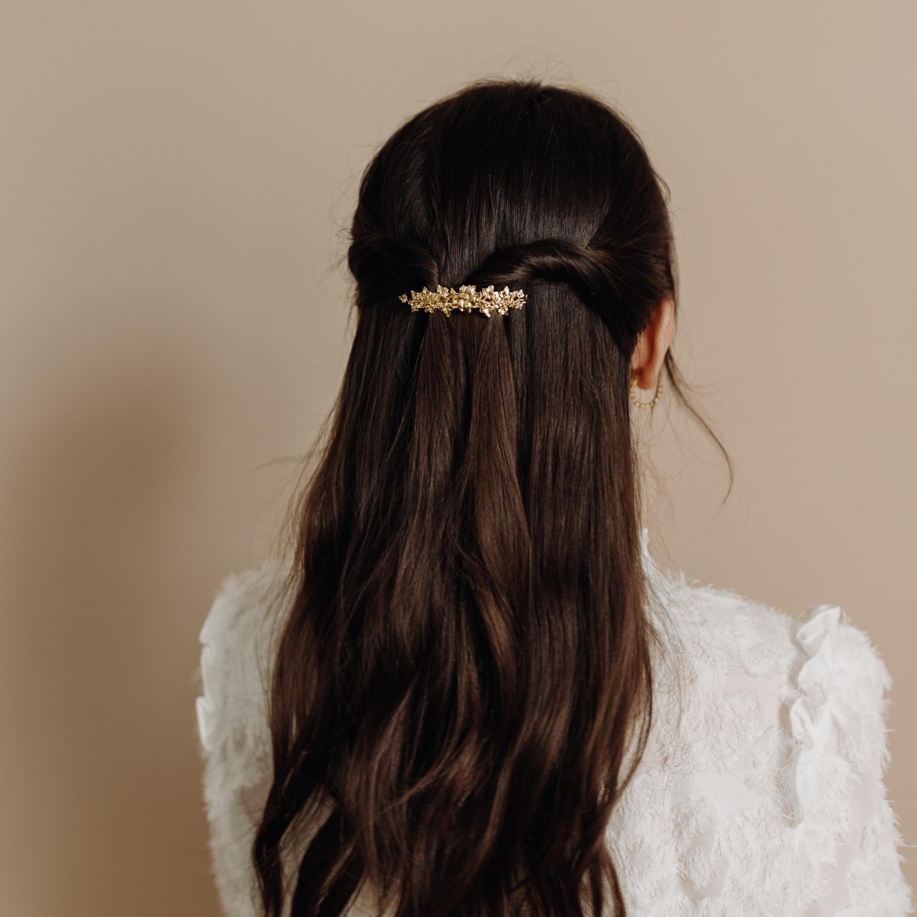 Femme cheveux longs coiffée avec une petite barrette dorée fleurie